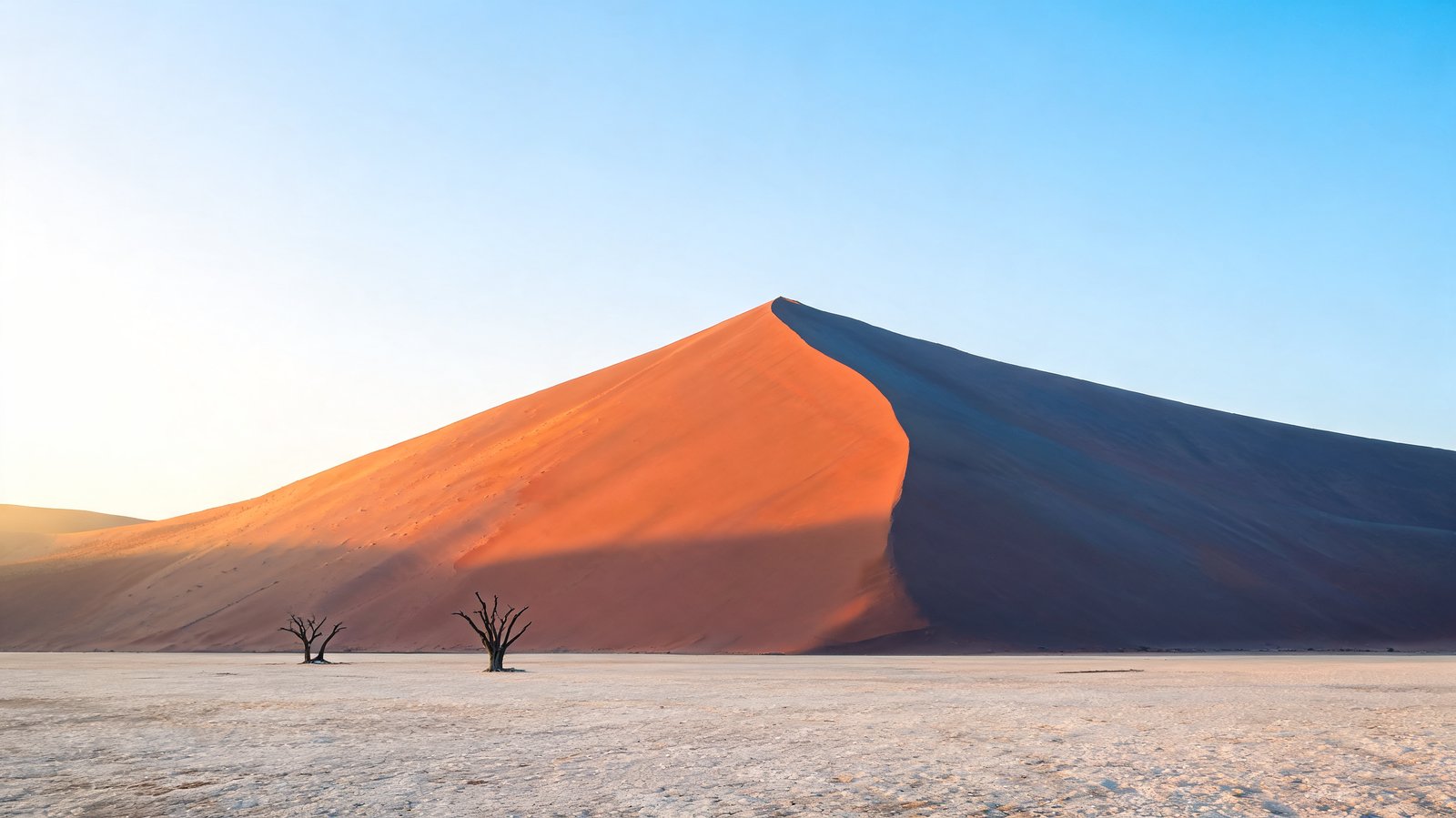 The sunlit ridge of a red dune above the clay pan at Sossusvlei, Namibia