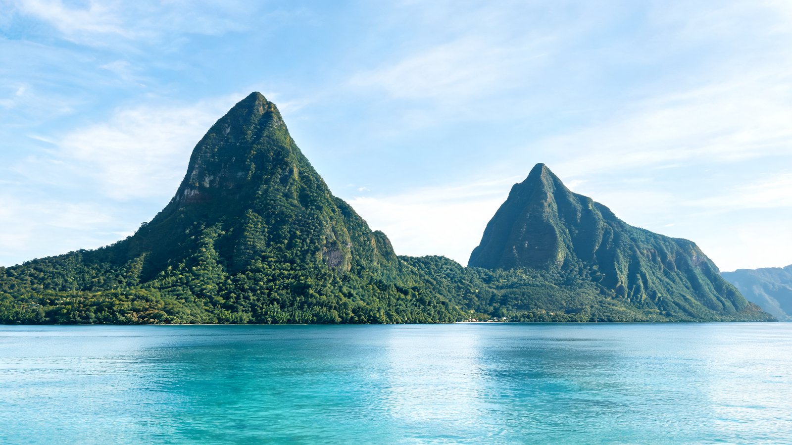 Both Piton peaks rising above rainforest and flat calm sea, St Lucia
