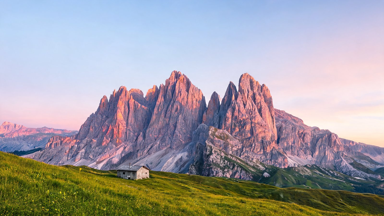 Vertical limestone faces catching first light above an alpine meadow and a stone rifugio, the Dolomites