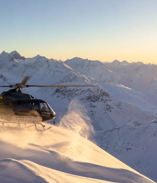 A helicopter landing on an untracked alpine ridge at sunrise