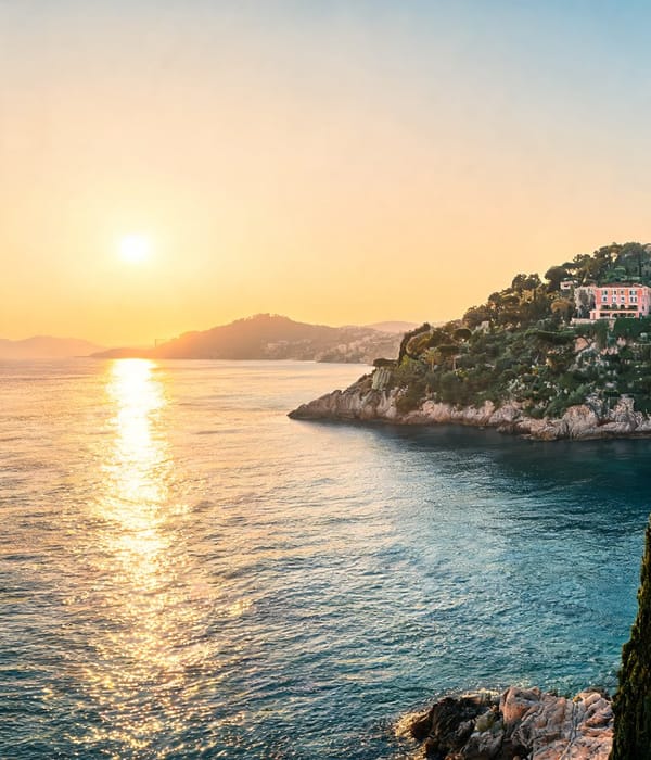 Sun setting over a turquoise cove below a headland above the water