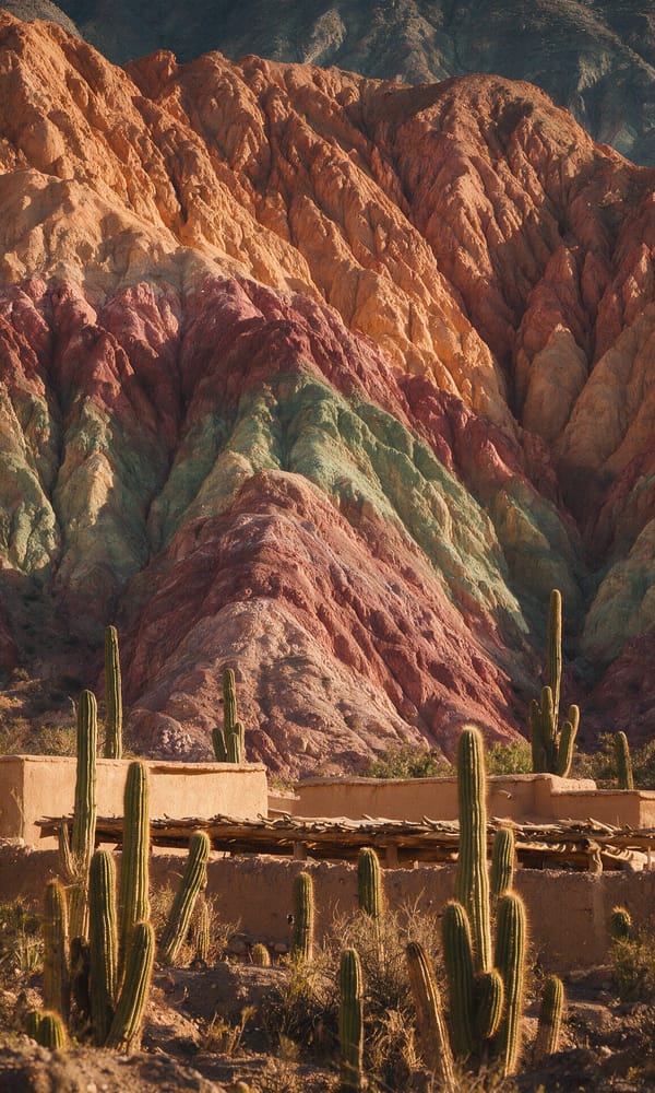 Banded ochre and rose rock rising above the adobe village of Purmamarca behind cardon cacti