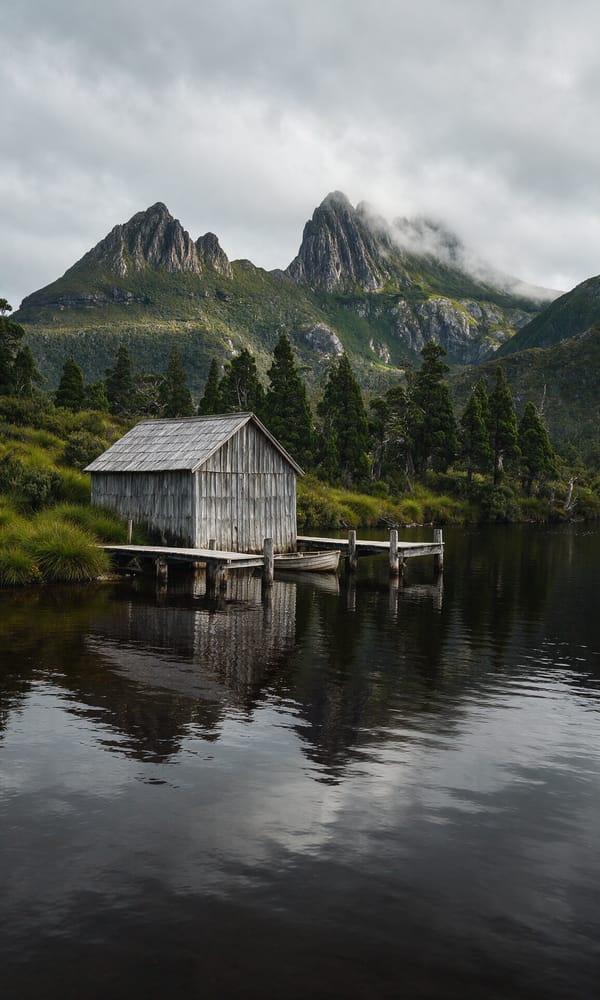 The timber boathouse on Dove Lake below the dolerite crags of Cradle Mountain in low cloud
