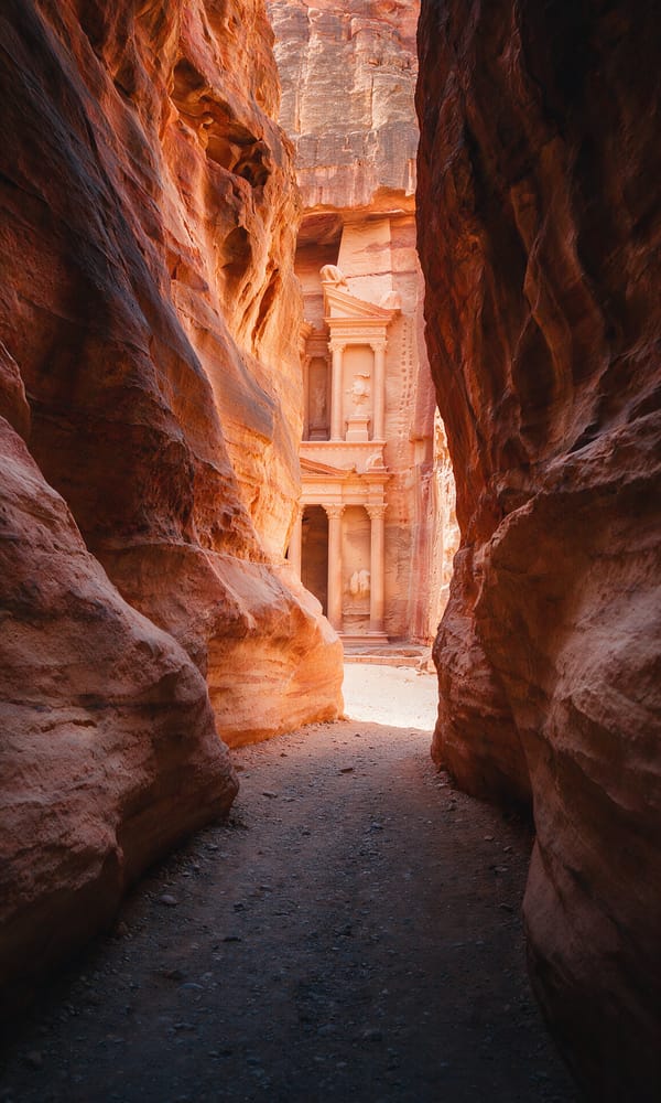 Sunlit columns of Petra's Treasury framed in the narrow shadowed walls of the Siq