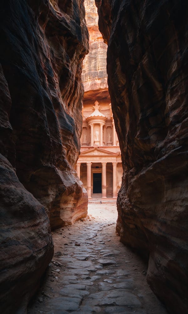 Petra's rose-red Treasury facade lit at the end of the shadowed Siq gorge
