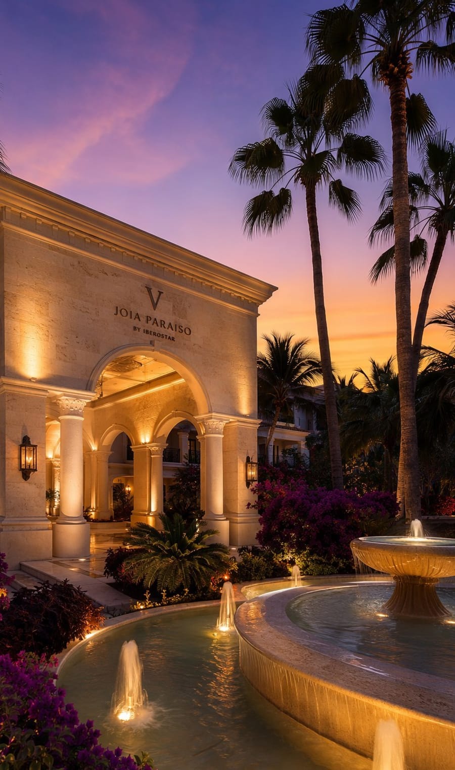 The lit entrance of a resort at dusk under palms