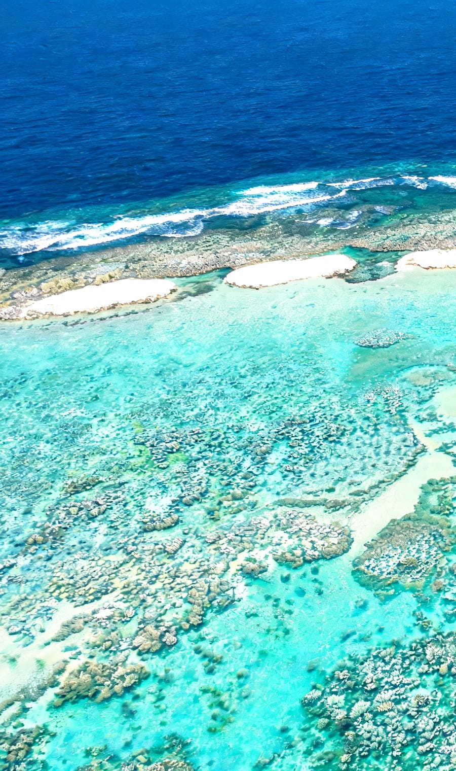 An aerial view of the barrier reef and turquoise lagoon shallows off Bora Bora