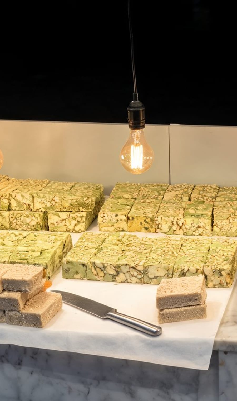 Slabs of halva under a bare bulb on a Jerusalem market counter