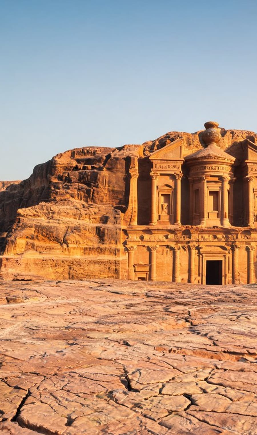 The rock-cut facade of Ad Deir standing above the open sandstone plateau at Petra in late light