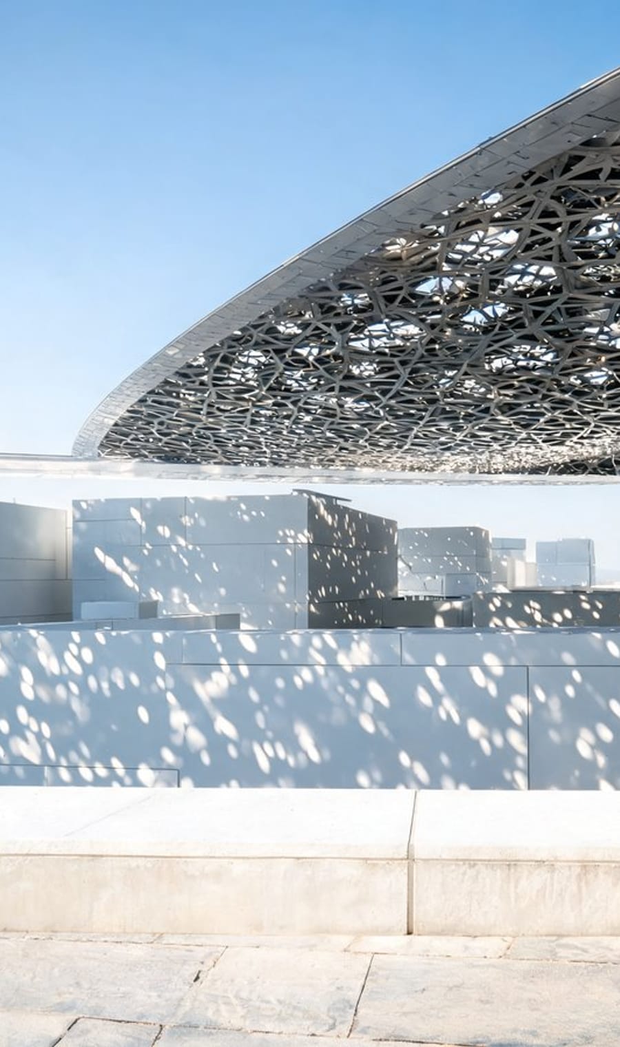 The perforated dome of the Louvre Abu Dhabi over its waterside courtyard